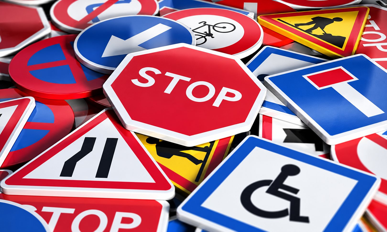 Un amas de panneaux de signalisation routière colorés, avec un grand panneau stop octogonal rouge au centre.