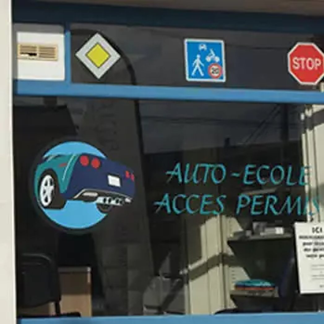 Vitrine bleue de l’agence Jules Haag avec le logo d’une voiture, des panneaux routiers et le lettrage « Auto-école Accès Permis ».
